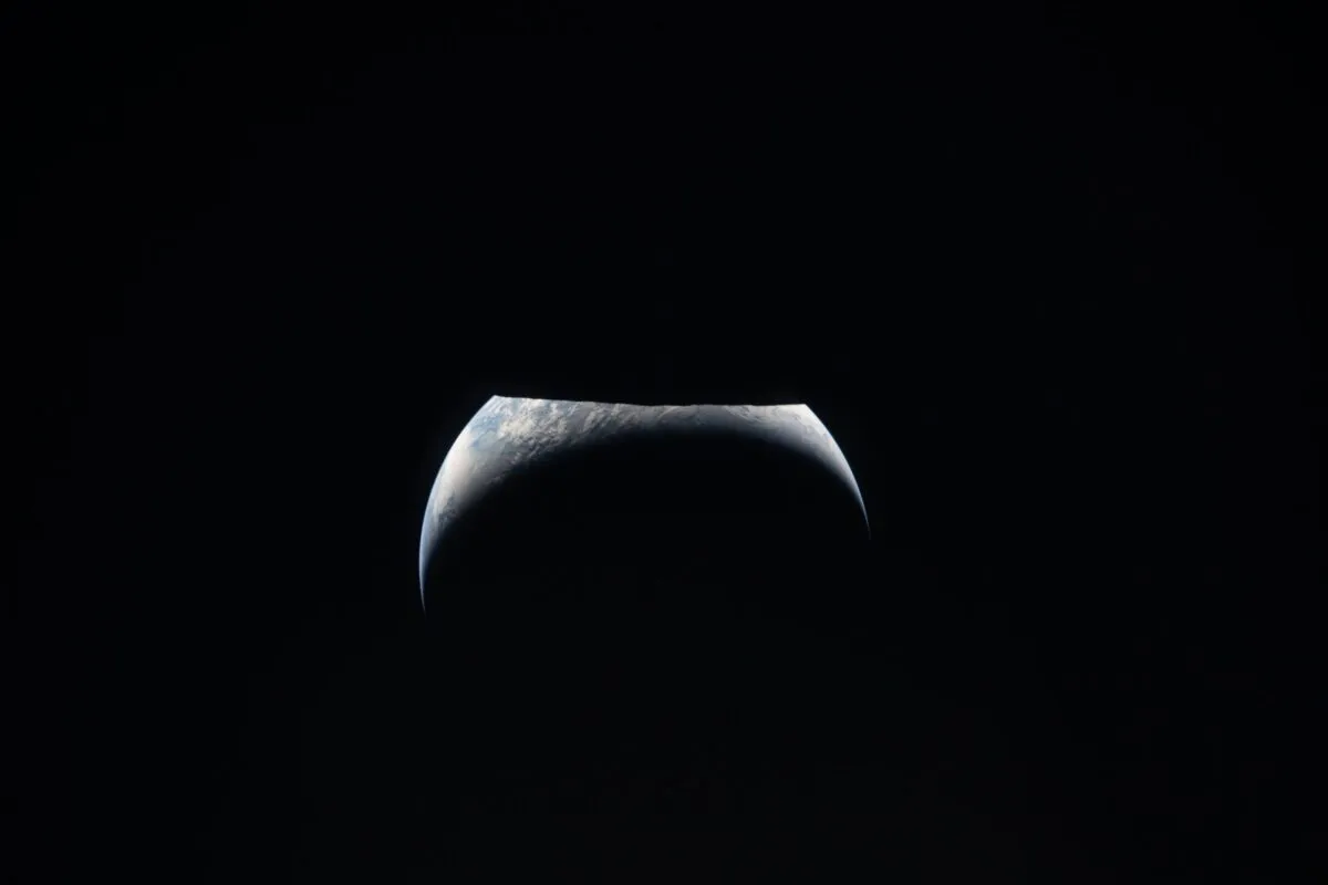 Tierra como creciente sobre el limbo lunar, vista desde la ventana de Orion durante el sobrevuelo de Artemis II