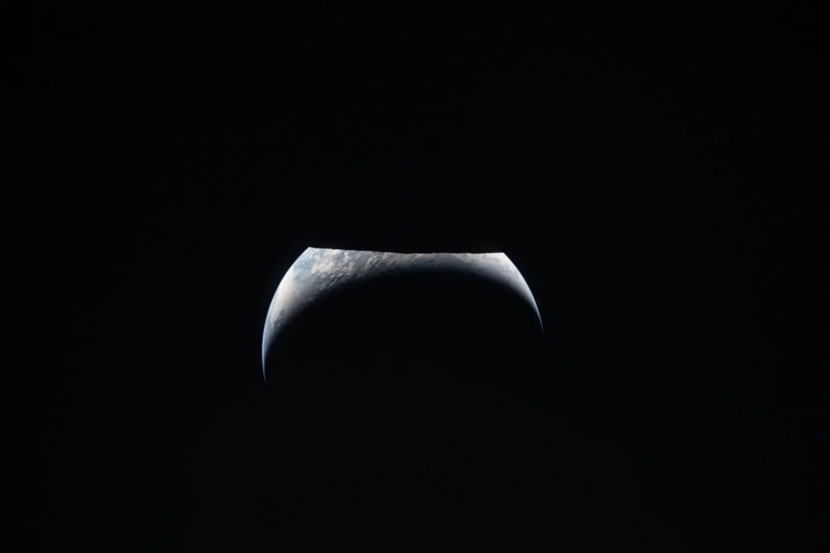 Tierra como creciente sobre el limbo lunar, vista desde la ventana de Orion durante el sobrevuelo de Artemis II